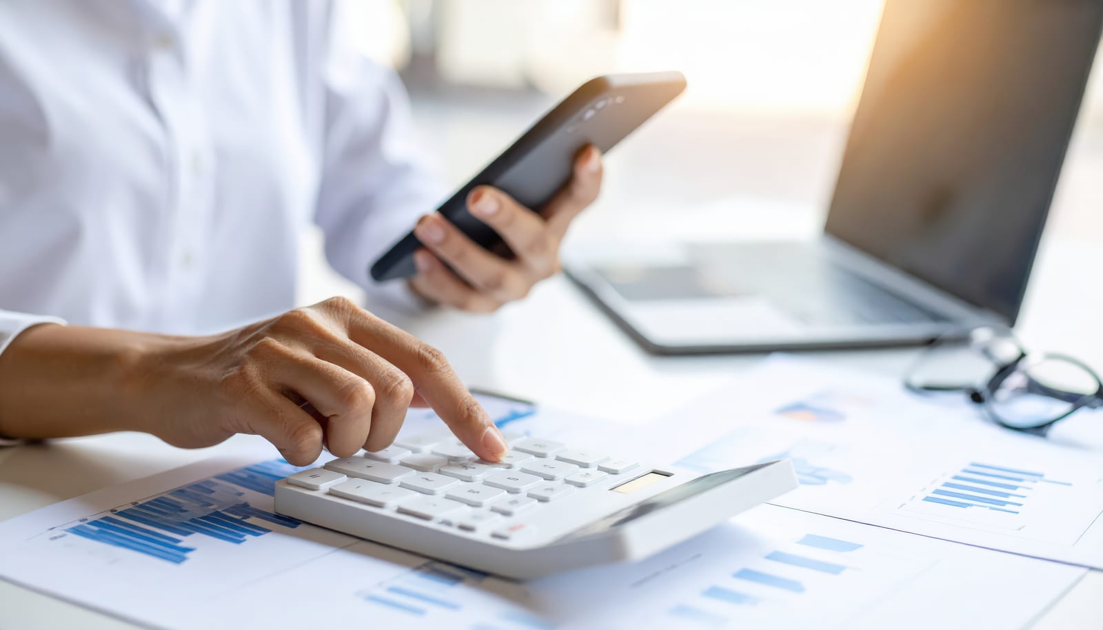 Working out borrowing capacity on a calculator beside financial statements.