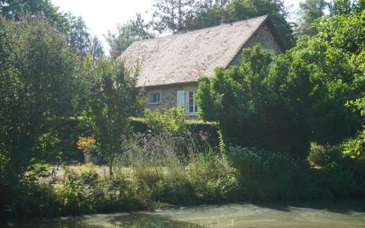 Charming stone house decorated with a pond and bordered by a river.